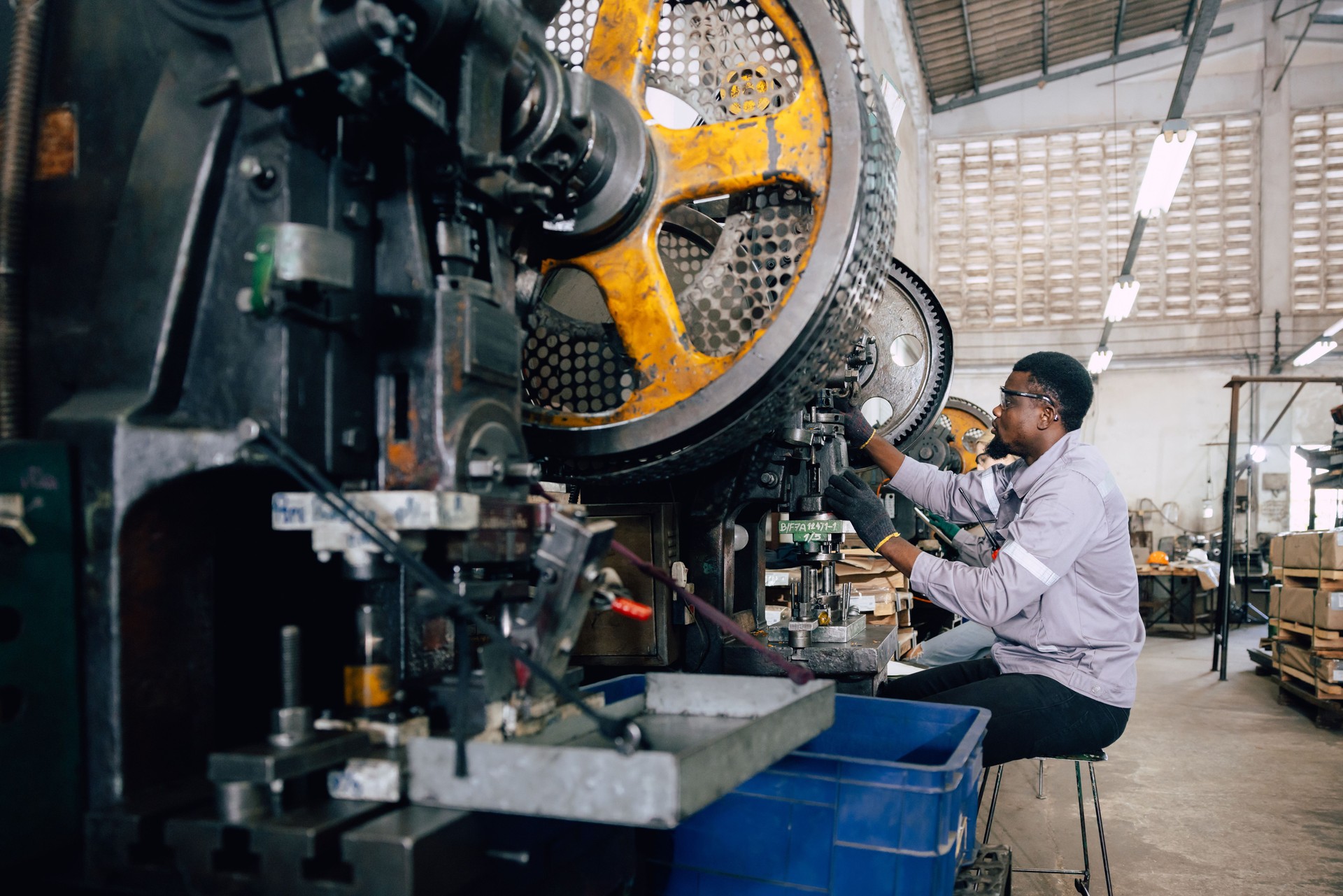 african black male worker working in heavy metal industry factory punching stamping steel machine