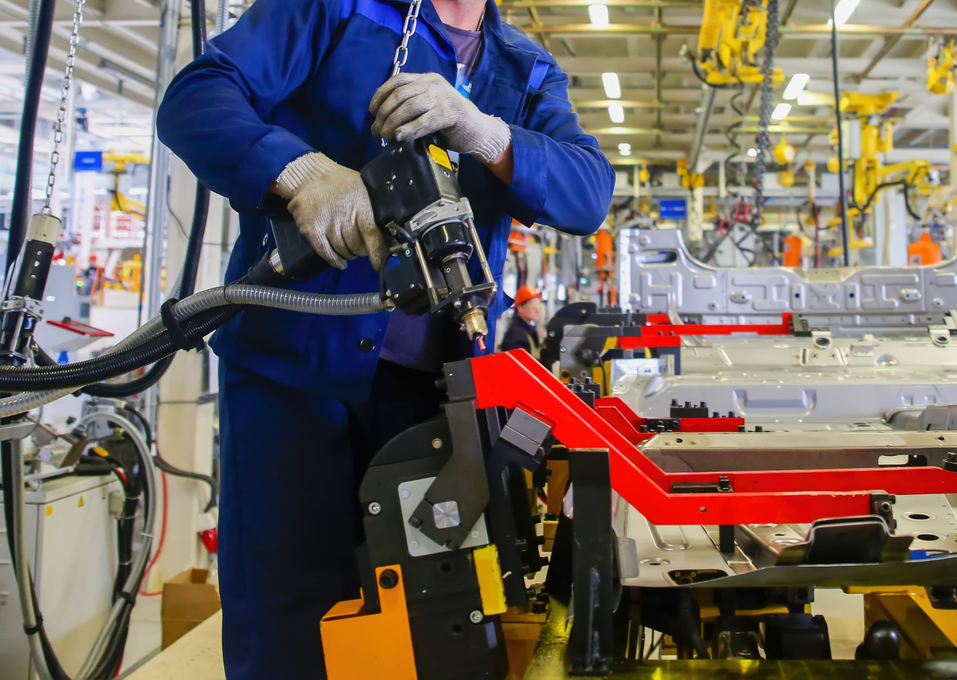Workers assemble automotive components in a manufacturing facility during the day