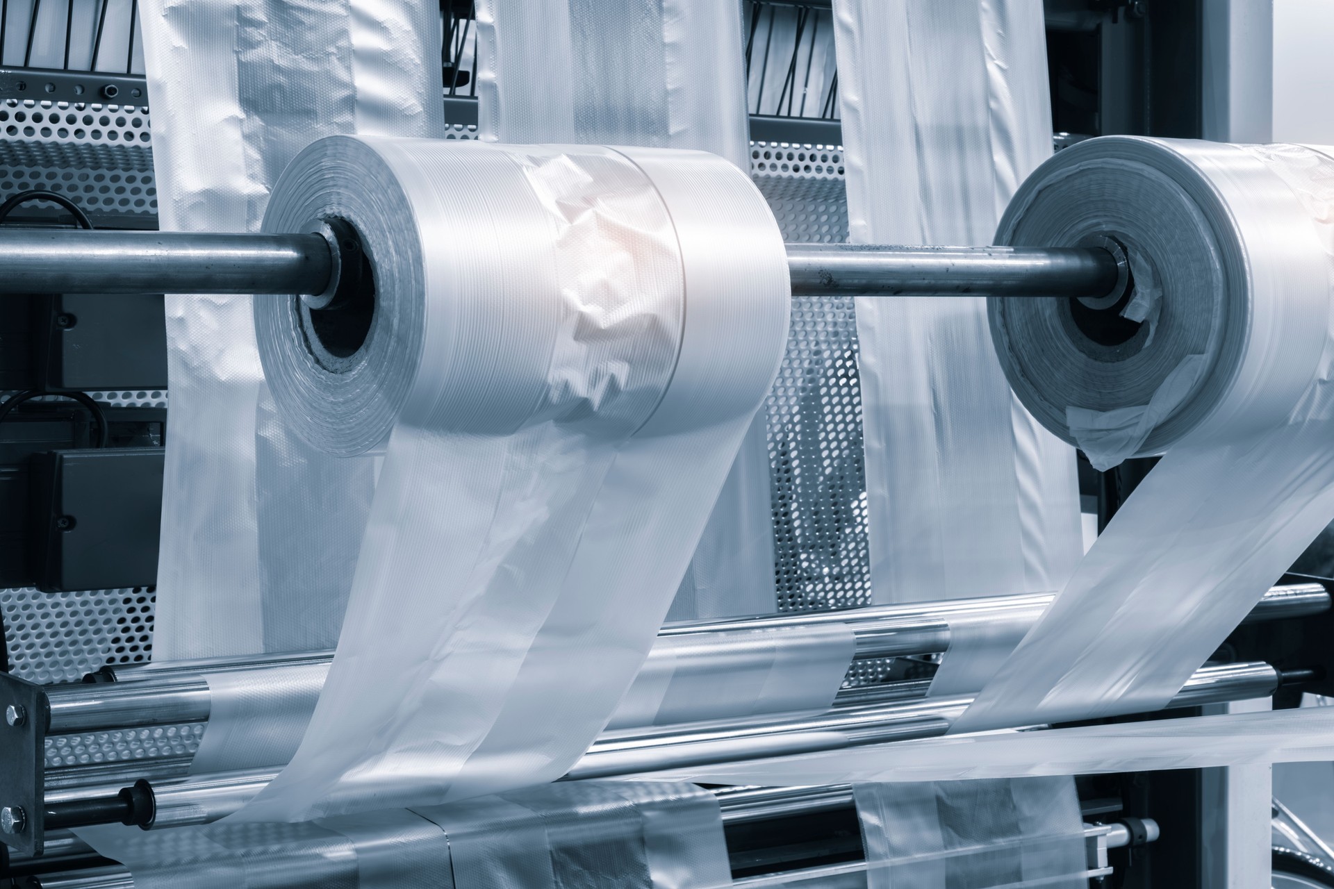 Automatic polyethylene plastic bag production machine with lighting effect. Close-up of the roller of the plastic bag production machine in the light blue scene. product packaging concept